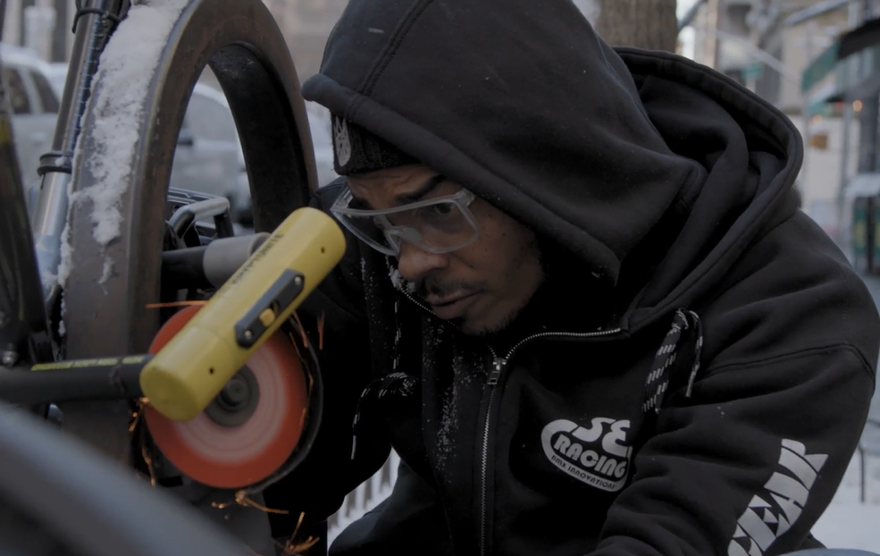 A man trying to brake the lock with an angle grinder.