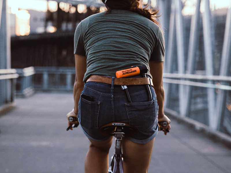 A person riding a bike with a lock in her pocket.